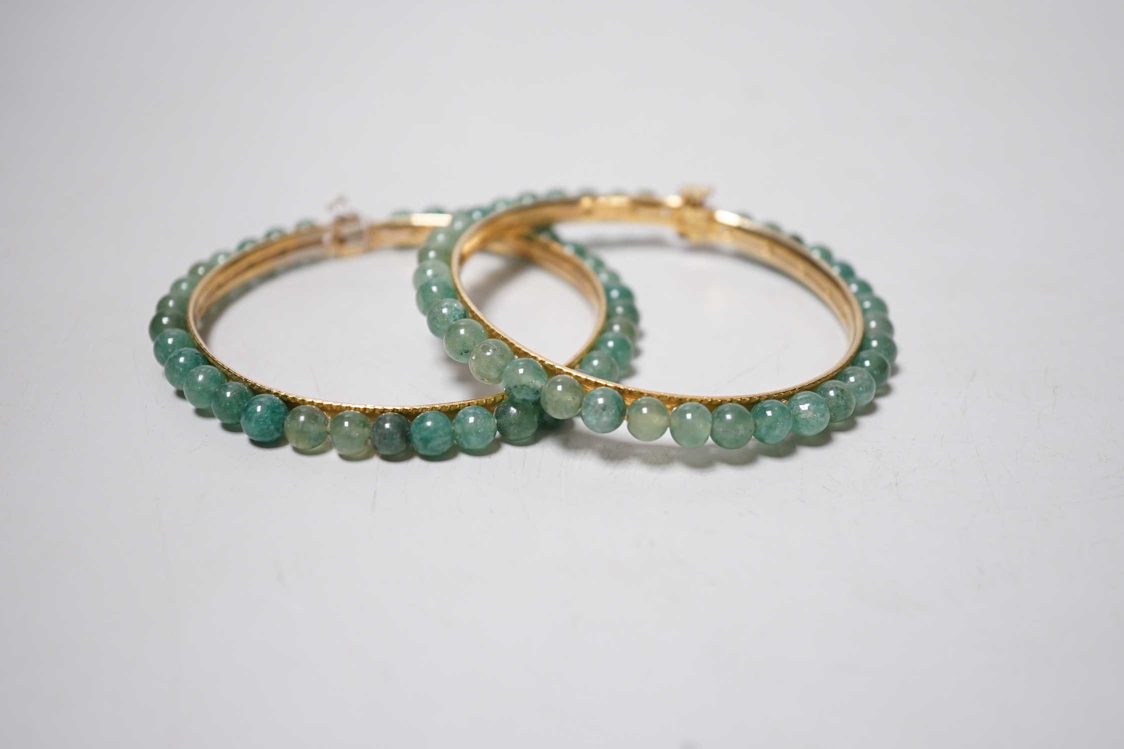 A pair of yellow metal and jade bangles, 7.2cm diameter
